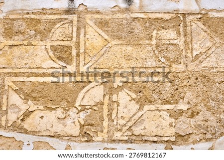 Ancient geometric etched patterns on weathered stone wall surface in warm earth tones.
