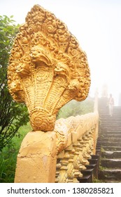 Ancient Golden Naga Stairs And Buddhist Tourist In Blue Misty. Wat Sampov Pram, Kampot, Cambodia. The Temple Is Open To The Public.