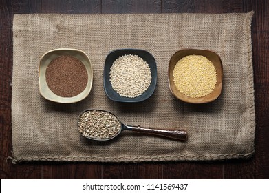 Ancient Grains of Teff, Sorghum, Millet and Buckwheat Isolated in Bowls and Scooper on a Burlap Sack.