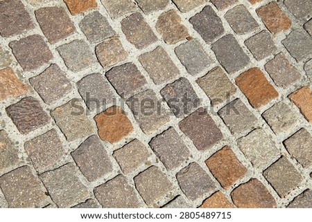 An ancient granite pavement, a path made of old cobblestones, background. A road in a European city.