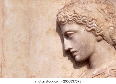 Ancient Greek relief of woman on marble wall with copy space for text. Remains of culture of past civilization in Greece. Beautiful stone sculpture, side view of face, old Greek art background.
