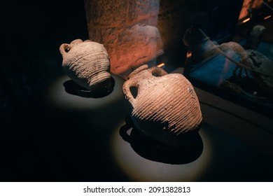 Ancient Greek Or Roman Amphora Was Made By Potters From Clay And Was Used To Transport Olive Oil And Wine. Illuminated Exhibit In Museum