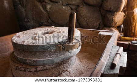 An ancient hand mill made of stones and wood. Flour grinding device. Authentic handicraft