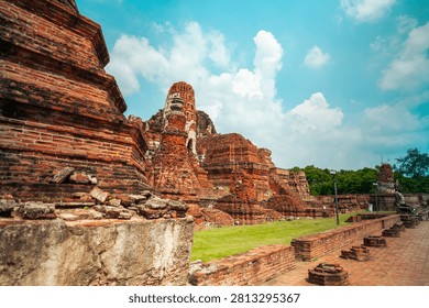 Ancient headless Buddha statues lining the red brick wall at Wat Mahathat in Ayutthaya, Thailand.