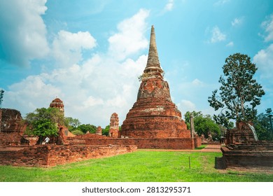 Ancient headless Buddha statues lining the red brick wall at Wat Mahathat in Ayutthaya, Thailand.