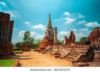 Ancient headless Buddha statues lining the red brick wall at Wat Mahathat in Ayutthaya, Thailand.