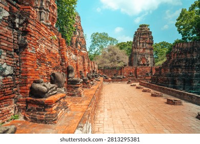 Ancient headless Buddha statues lining the red brick wall at Wat Mahathat in Ayutthaya, Thailand.