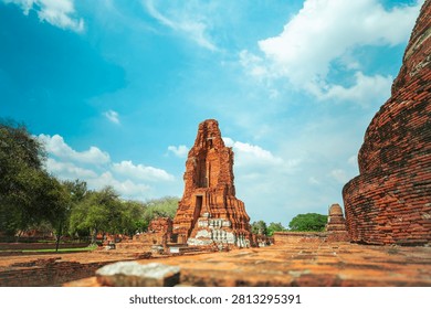 Ancient headless Buddha statues lining the red brick wall at Wat Mahathat in Ayutthaya, Thailand.
