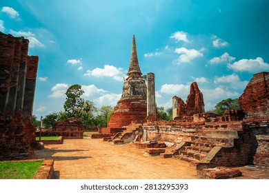 Ancient headless Buddha statues lining the red brick wall at Wat Mahathat in Ayutthaya, Thailand.