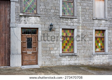 Ancient house with gray brick wall and colorful windows