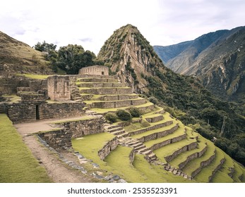 An ancient Inca ruins site with stone structures and terraced gardens nestled in a lush, mountainous landscape - Powered by Shutterstock