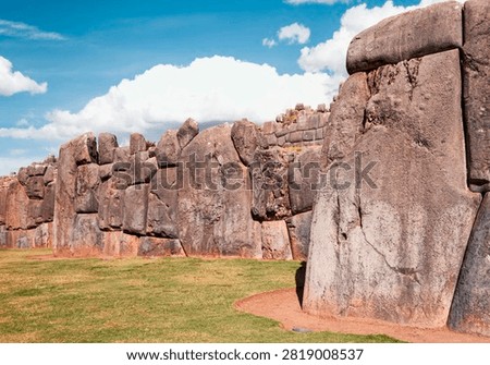 Ancient Inca stonework rises in precise, interlocking forms beneath a shifting Andean sky (Cusco, Peru: 06-may-2009)