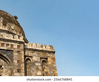 Ancient Indian building. Mughal stone architecture with decorative carvings, old dome. Historical structure from Lodhi Gardens, blue sky background. - Powered by Shutterstock