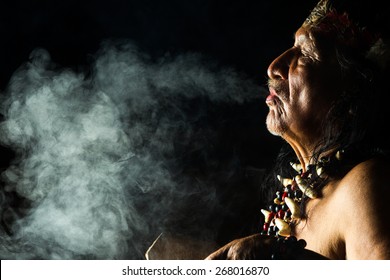 An ancient indigenous tribe in the Amazon, Ecuador, performs a sacred ayahuasca ritual led by a shaman, engulfed in smoke and ancient medicine.