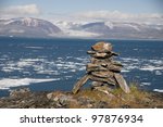 An ancient Inuit inukshuk serves as a landmark for seafarers in a fjord of Baffin Island, Nunavut, Canada.  This inukshuk is estimated to be at least one thousand years old.