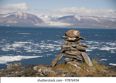 An ancient Inuit inukshuk serves as a landmark for seafarers in a fjord of Baffin Island, Nunavut, Canada.  This inukshuk is estimated to be at least one thousand years old. - Powered by Shutterstock