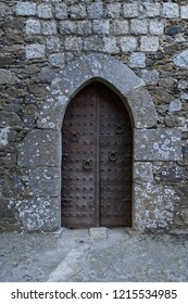 Ancient iron gates of a medieval castle with knockers and rustic studs
