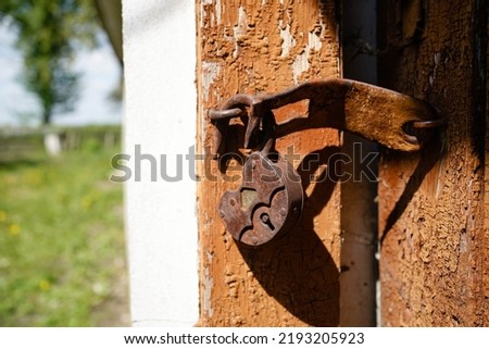 An ancient lock covered with rust hangs on the door
