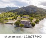 Ancient Marae Taputapuatea temple complex on the lagoon shore with mountains on background. Raiatea island. Leeward / Society Islands, French Polynesia, Oceania, South Pacific Ocean. Aerial view.