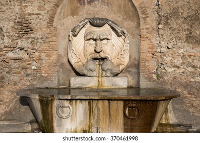 Ancient marble fountain with mask from frowning and bushy mustache. One of the beauties of Rome