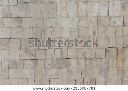 Ancient masonry wall of the Mayan temple in the city of Chichen Itza. The wall is made of stone blocks.