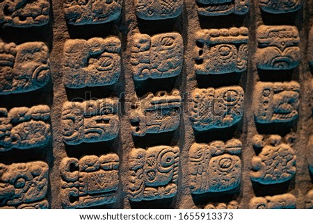 Ancient Mayan glyphs/pictograms carved in a stone slab.
