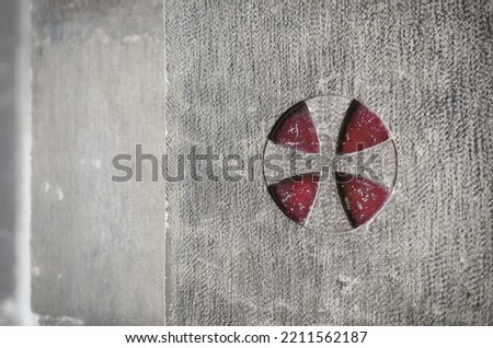 Ancient medieval templar cross engraved over the external stone wall of the cathedral of Lisbon, Portugal