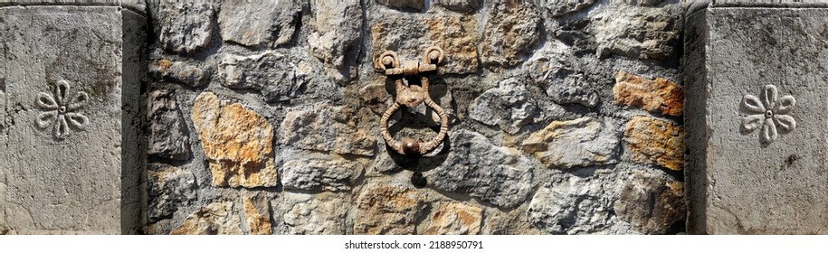 Ancient Mediterranean Stone And Rusty Iron Ornaments Ona A Cobble Stone Wall