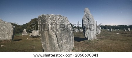 Ancient menhir granite stones at night, close-up. Clear sky, stars, moonlight. Carnac, France. Atmospheric landscape. Travel destinations, tourism, national landmark, sightseeing. culture, history