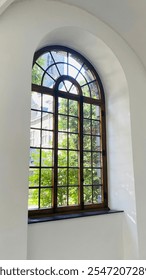 An ancient monastery window, framed by worn wood and delicate details. Its aged glass catches the light, offering a glimpse into history while the atmosphere feels both peaceful.