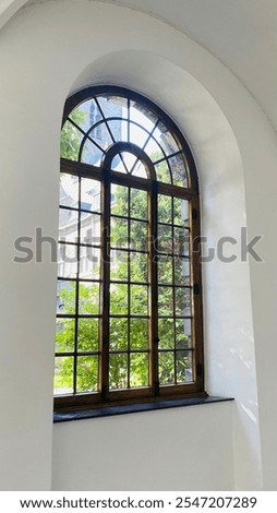 An ancient monastery window, framed by worn wood and delicate details. Its aged glass catches the light, offering a glimpse into history while the atmosphere feels both peaceful.