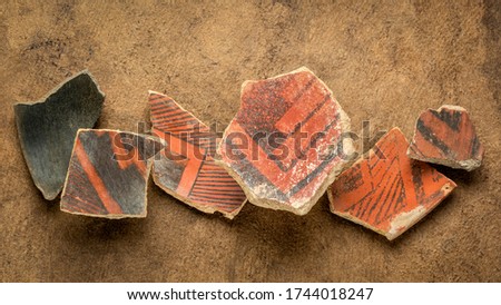 ancient Native American Indian (Anasazi) artifacts, several pottery fragments  on a textured  paper background