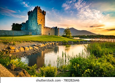Ancient old Fortress Ross Castle ruin with a lake, green grass and orange clouds in Ireland during golden hour nobody