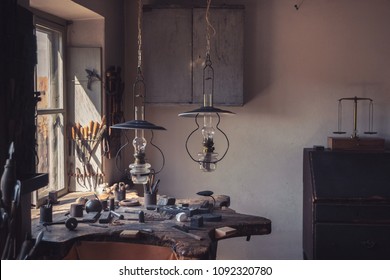 Ancient old-fashioned lamp and hand tools in antique rustic country workshop of silver and gold maker. Very old things near windowsill by stone wall background. Vintage decorative lamp hanging indoors - Shutterstock ID 1092320780