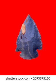 Ancient Prehistoric Primitive Stone Arrowhead Isolated Over Red