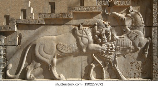 An ancient relief on the wall of the ruined city of Persepolis. The Lion attacks the bull. This image symbolizes fertility of earth and cycles of year. Iran.