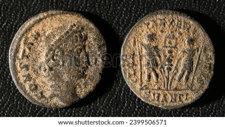 Ancient Roman coin of Emperor Constantius II, top view of vintage metal money isolated on black background. Theme of old grungy copper texture, Rome, Empire, antique and history.