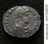 Ancient Roman coin of Emperor Theodosius I the Great, top view of vintage metal money isolated on black background. Concept of old copper texture, Rome, Byzantine Empire, antique and history. 