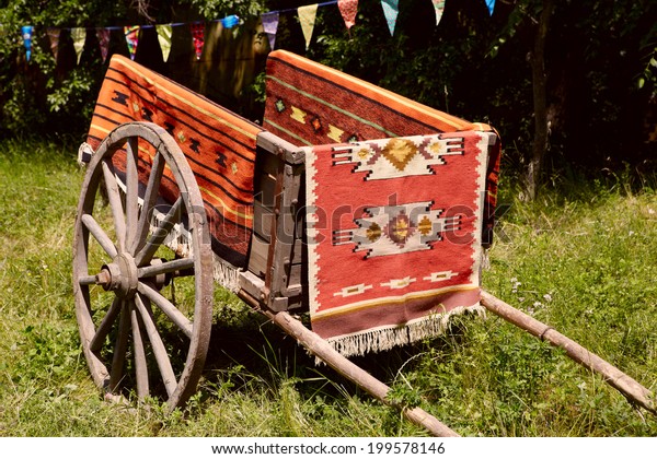 Ancient\
Romanian wooden cart standing on a green\
grass