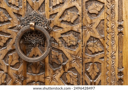 Ancient round copper handle of an old wooden door decorated with carved Arabic ornaments