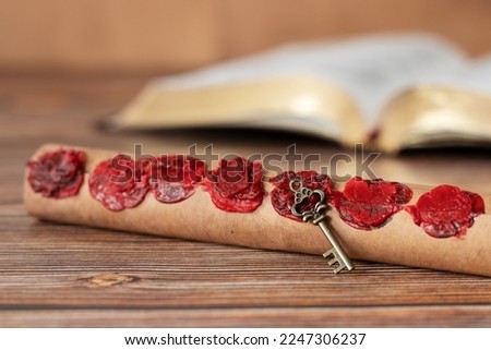 Ancient scroll with seven seals with old key on wooden table with holy bible book. A closeup. Christian prophecy, apocalypse, revelation of God Jesus Christ, biblical concept. Selective focus.