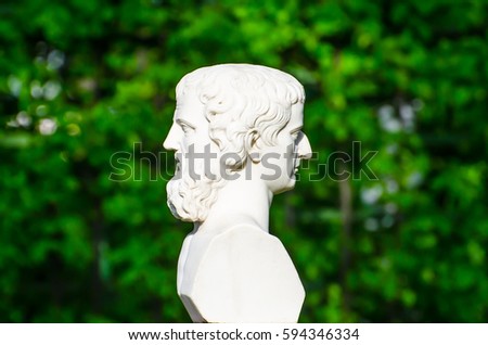 Ancient sculpture head on both sides conceptually profile of a human face in the park