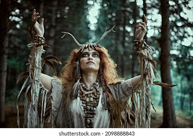 An Ancient Shaman Woman In Ritual Garment Performs A Traditional Mystical Shamanic Ritual In The Forest. Fairy Forest Witch. Fantasy. Halloween. 