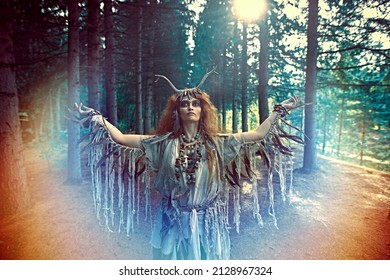 An Ancient Shaman Woman In Ritual Garment Performs A Traditional Mystical Shamanic Ritual In The Forest. Fairy Forest Witch. Fantasy. Halloween. 