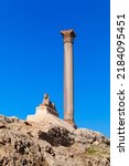 Ancient sphinx with Pompeys Pillar on a background, vertical photo. Alexandria, Egypt