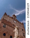 The ancient statue of the well-known Prato merchant Francesco Datini with Palazzo Pretorio in the background, located in the Piazza del Comune of Prato, Italy