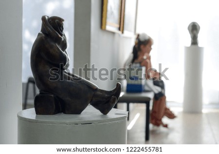 Ancient statuette on the background of sitting people.