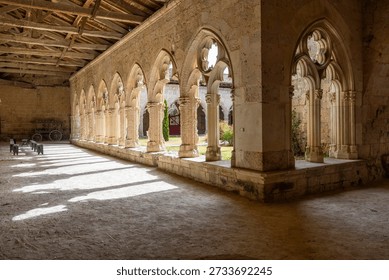 Ancient stone arcade creating patterns of light and shadow on the ground in a historical cloister