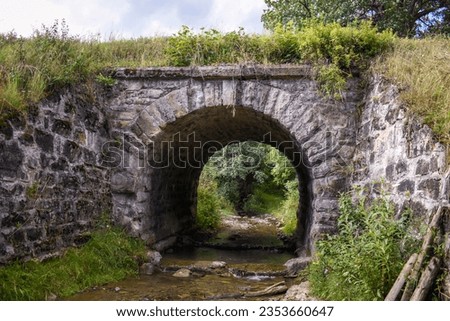 Ancient stone arch, old stone bridge across a small river