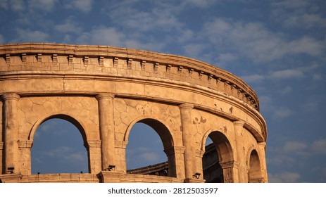 Ancient stone arch structure captured under a clear blue sky with warm light and curved arches